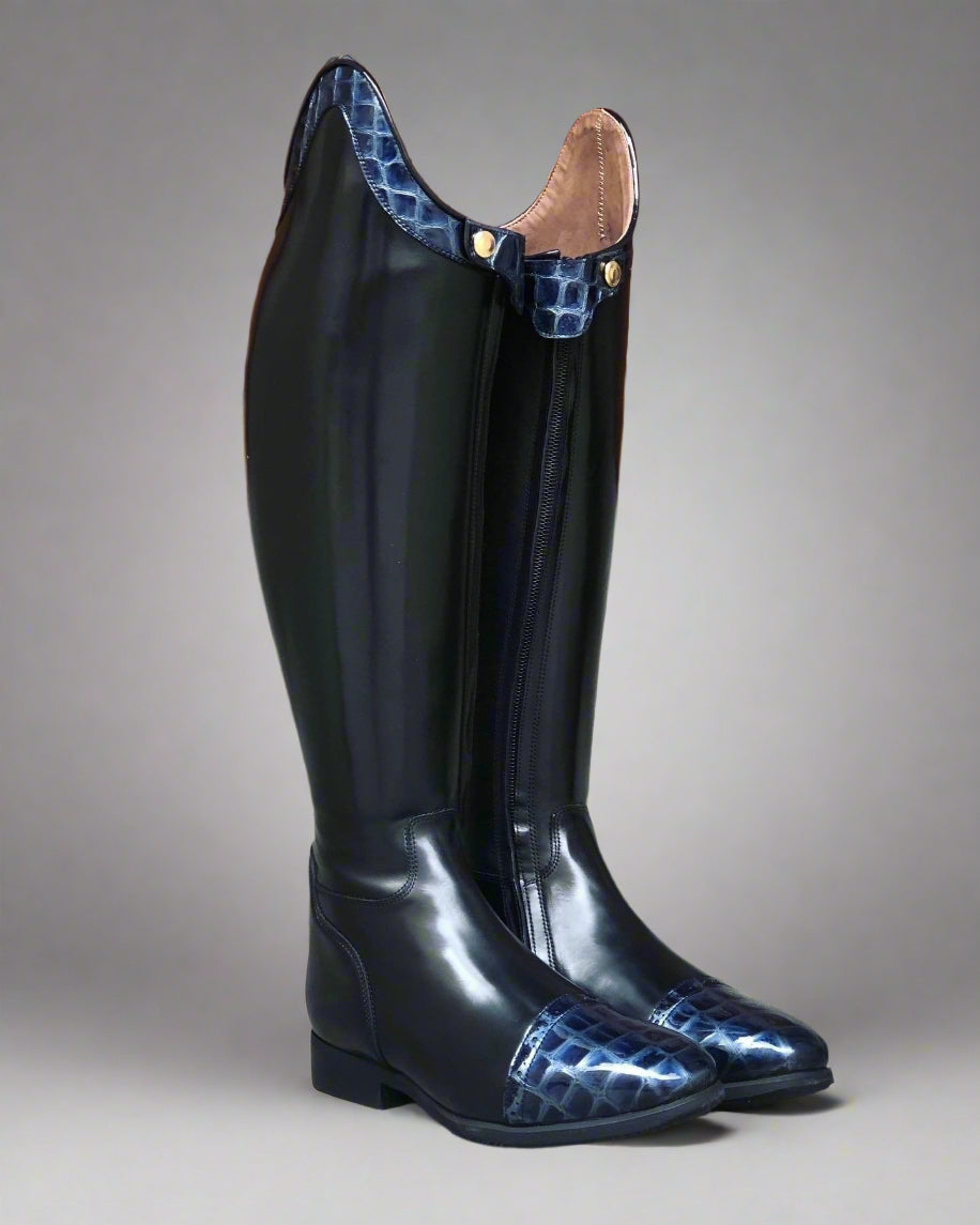 A black riding boot with a blue crocodile pattern on the sole, featuring a zipper and a push button.